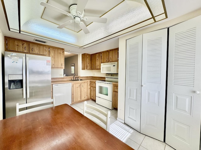 kitchen with white appliances, light tile patterned flooring, visible vents, and a sink