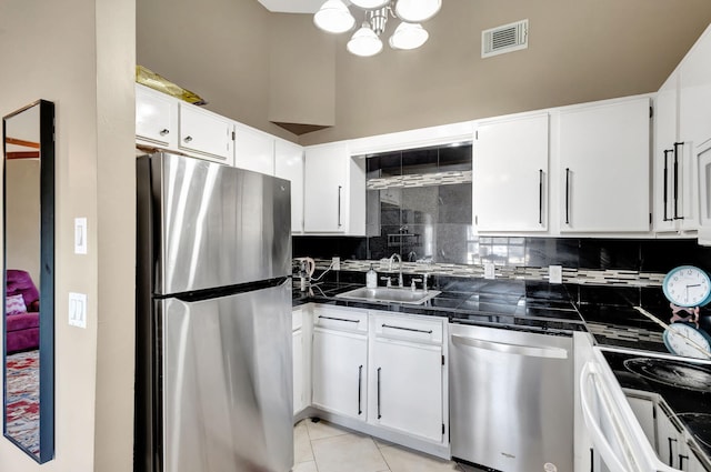 kitchen featuring backsplash, appliances with stainless steel finishes, a sink, white cabinets, and a chandelier