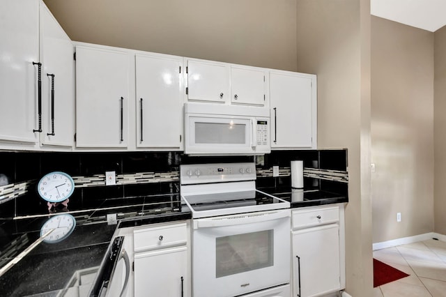 kitchen with dark countertops, backsplash, white cabinets, and white appliances