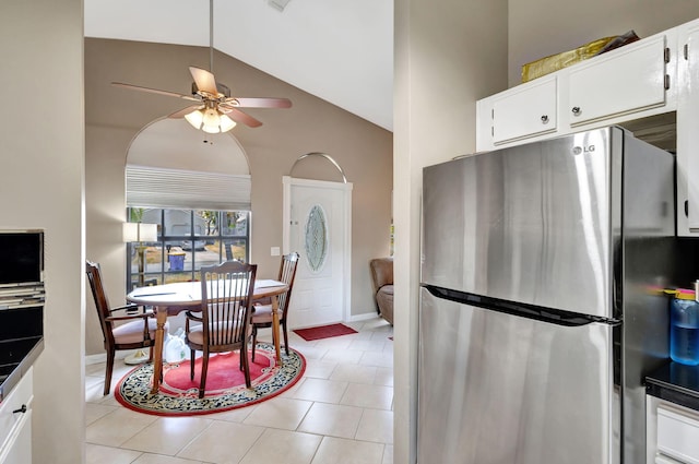kitchen with ceiling fan, vaulted ceiling, white cabinets, freestanding refrigerator, and light tile patterned flooring