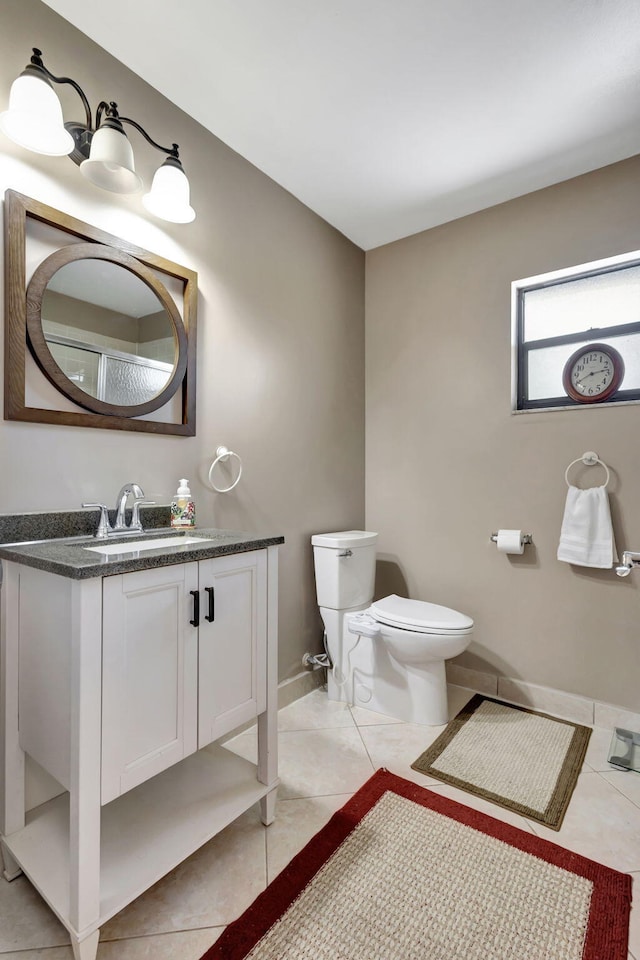 bathroom with vanity, baseboards, tile patterned floors, and toilet