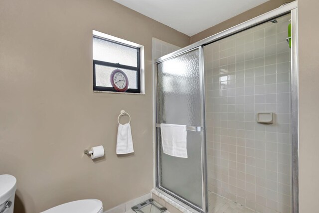 full bath with baseboards, tile patterned flooring, toilet, and tiled shower