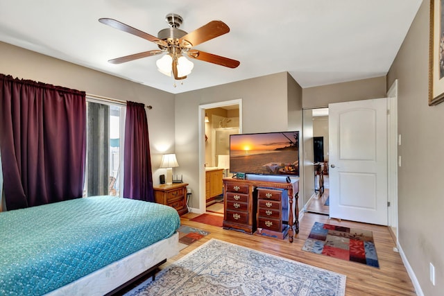 bedroom featuring baseboards, ceiling fan, light wood finished floors, and ensuite bath