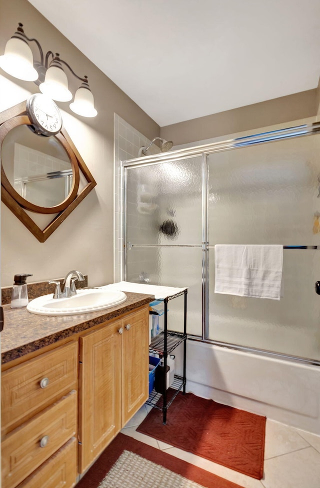 bathroom with tile patterned flooring, bath / shower combo with glass door, and vanity