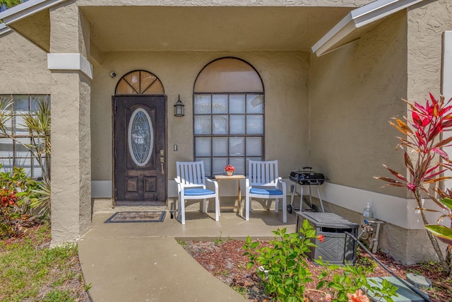 doorway to property featuring covered porch and stucco siding