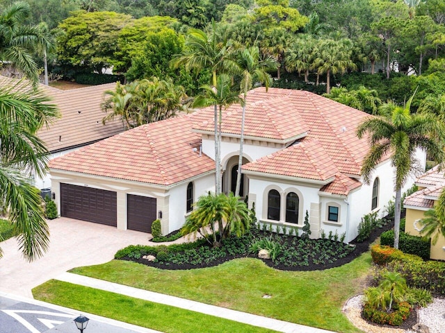 view of front facade with a front lawn, stucco siding, an attached garage, driveway, and a tile roof
