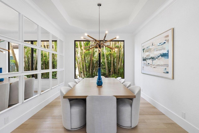dining room featuring a raised ceiling, light wood finished floors, a chandelier, and a wealth of natural light