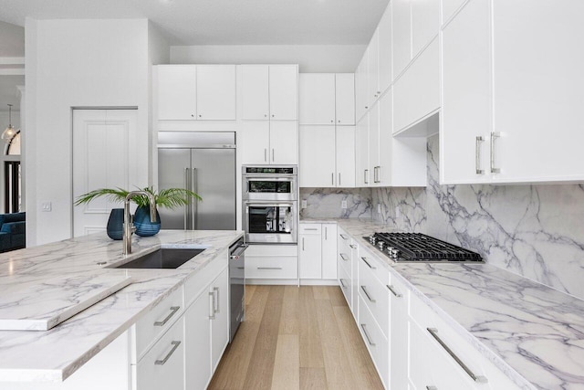 6581 Grande Orchid Way, Delray Beach, FL 33446 - kitchen featuring stainless steel appliances, light wood-style flooring, white cabinetry, decorative backsplash, and light stone counters