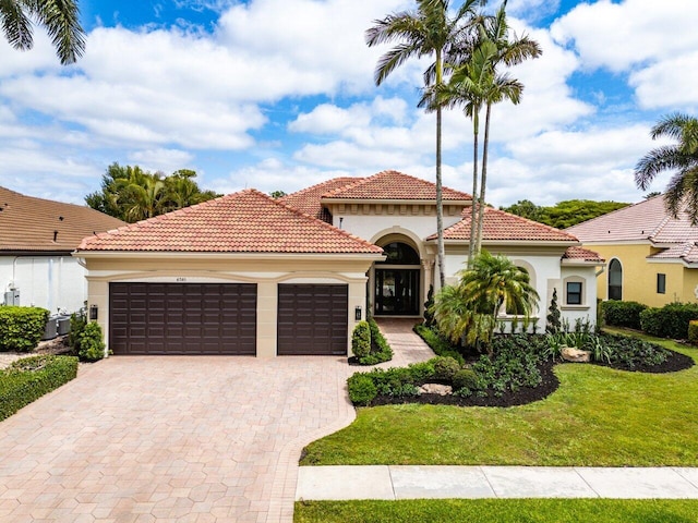 mediterranean / spanish house with an attached garage, decorative driveway, stucco siding, and a tile roof