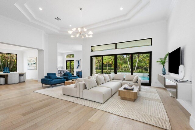 6581 Grande Orchid Way, Delray Beach, FL 33446 - living room with a chandelier, light wood finished floors, a tray ceiling, a towering ceiling, and crown molding