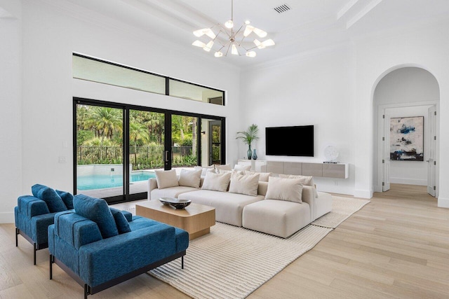 6581 Grande Orchid Way, Delray Beach, FL 33446 - living room featuring a chandelier, a towering ceiling, arched walkways, crown molding, and light wood-type flooring