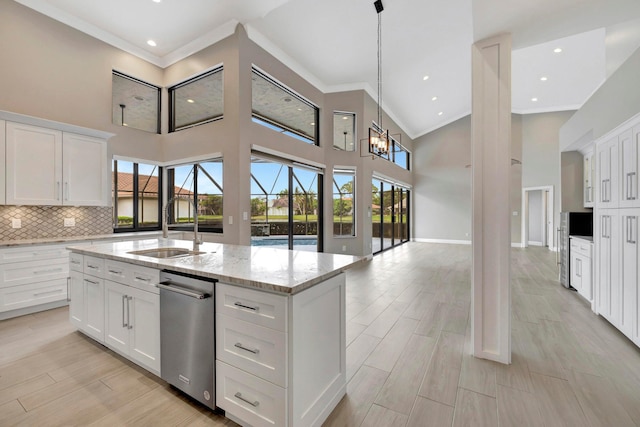 kitchen with crown molding, white cabinets, light stone countertops, and a towering ceiling