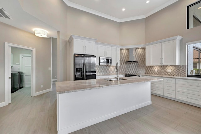 kitchen featuring a sink, separate washer and dryer, wall chimney exhaust hood, stainless steel appliances, and visible vents