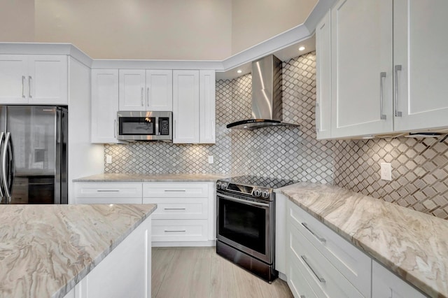 kitchen with wall chimney range hood, white cabinetry, appliances with stainless steel finishes, and tasteful backsplash