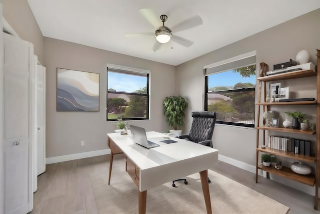 office space with baseboards, ceiling fan, and a healthy amount of sunlight