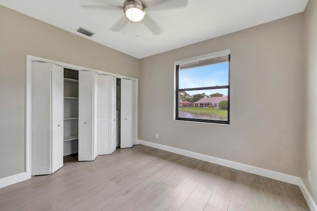 unfurnished bedroom with multiple closets, baseboards, visible vents, and light wood-style floors