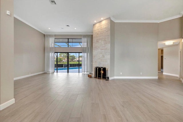 unfurnished living room featuring crown molding, baseboards, and light wood-style floors