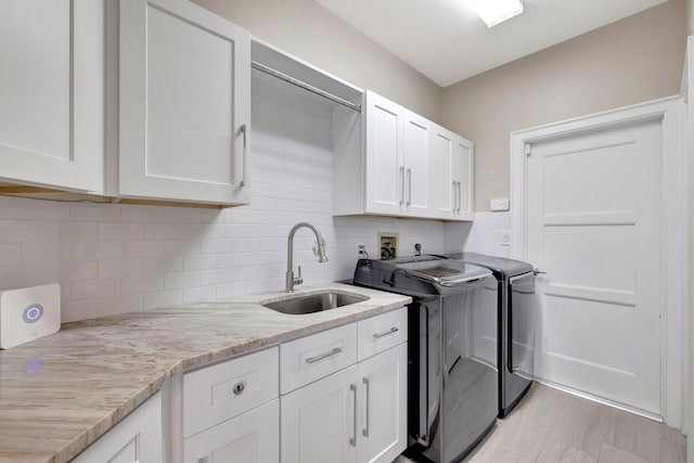 laundry area with washing machine and clothes dryer, a sink, and cabinet space