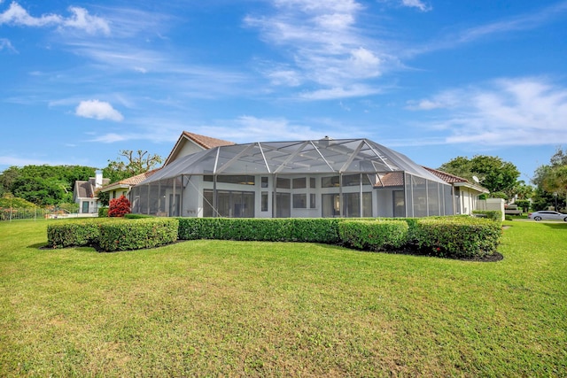 back of property with a yard and glass enclosure