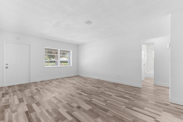 9603 NW 72nd Mnr, Tamarac, FL 33321 - unfurnished living room featuring a textured ceiling, baseboards, and light wood-type flooring