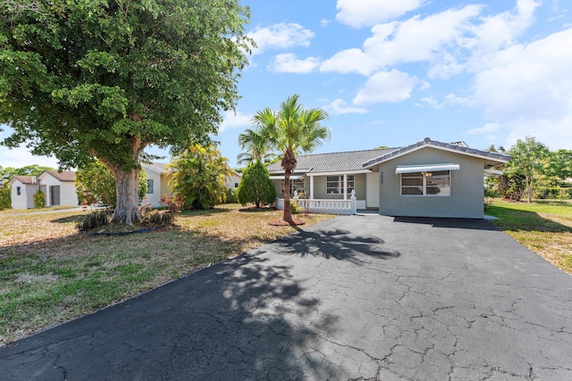 9603 NW 72nd Mnr, Tamarac, FL 33321 - view of front of home with a front lawn, aphalt driveway, covered porch, stucco siding, and a tiled roof