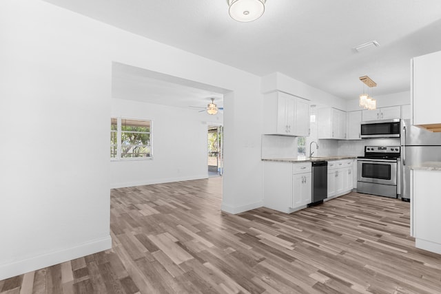9603 NW 72nd Mnr, Tamarac, FL 33321 - kitchen with open floor plan, light wood-type flooring, white cabinetry, tasteful backsplash, and stainless steel appliances