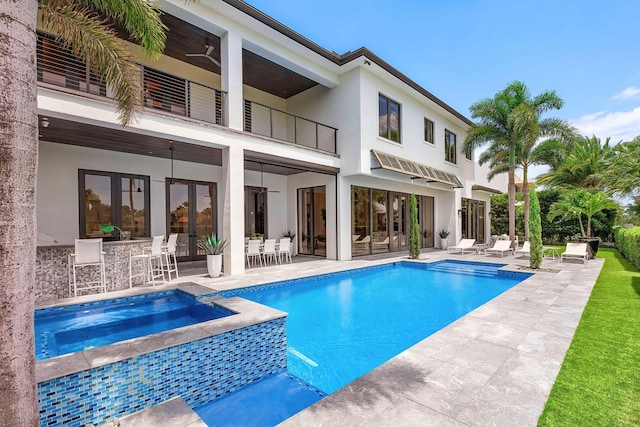 view of pool featuring a patio, exterior bar, a ceiling fan, french doors, and a pool with connected hot tub