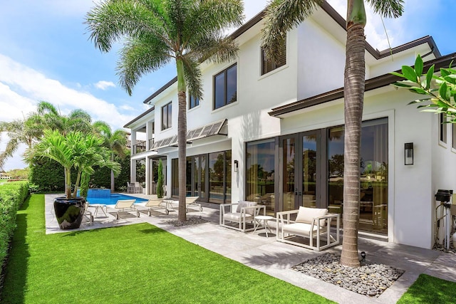 rear view of property with stucco siding, a yard, an outdoor pool, and a patio