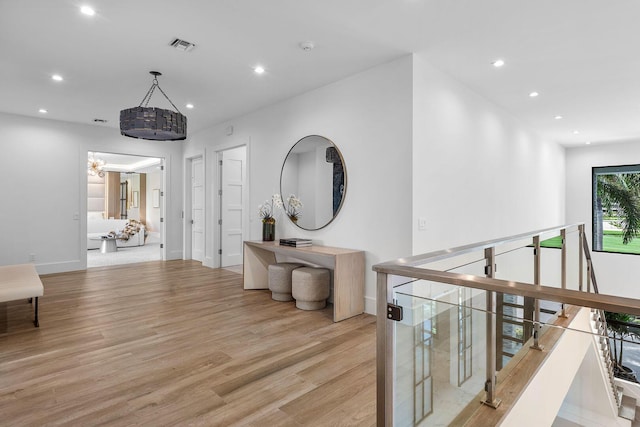 hallway featuring light wood-type flooring, recessed lighting, baseboards, a chandelier, and an upstairs landing
