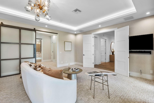 living area featuring light colored carpet, a tray ceiling, recessed lighting, a barn door, and a chandelier