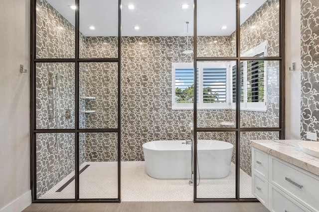 full bath with a soaking tub, walk in shower, and vanity