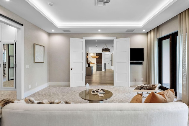 carpeted living room with a tray ceiling, baseboards, and recessed lighting