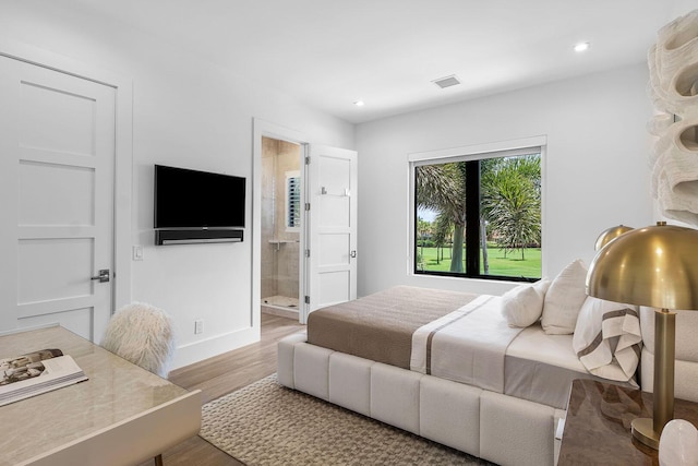 bedroom featuring wood finished floors, baseboards, recessed lighting, and connected bathroom