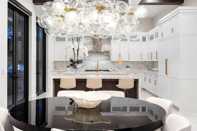 kitchen featuring wall chimney range hood, decorative backsplash, a kitchen island, and white cabinets