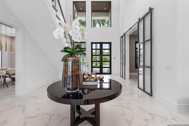 foyer with marble tiled flooring, baseboards, and a high ceiling