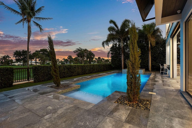 pool at dusk with a patio and a fenced backyard
