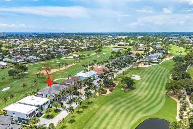 aerial view of property and surrounding area featuring nearby suburban area, a large body of water, and a golf course