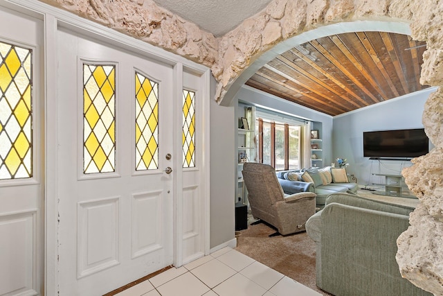 carpeted foyer entrance with arched walkways, lofted ceiling, wood ceiling, and tile patterned flooring