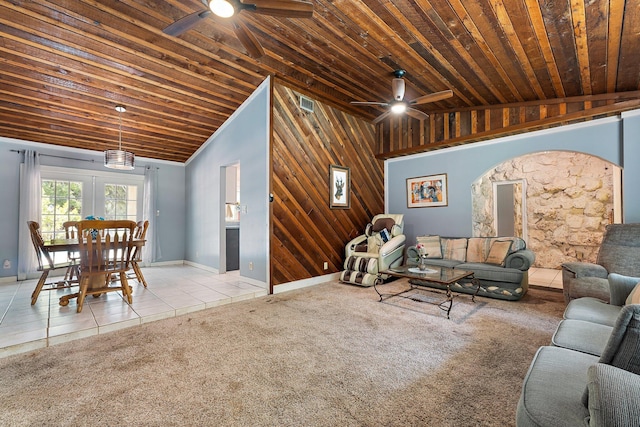 tiled living area featuring wood ceiling, a ceiling fan, vaulted ceiling, wooden walls, and carpet flooring