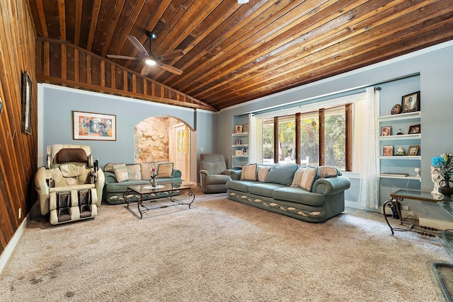 living area featuring a ceiling fan, carpet flooring, built in shelves, arched walkways, and vaulted ceiling