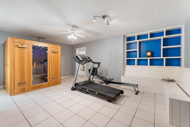 exercise area with a textured ceiling, ceiling fan, baseboards, and tile patterned flooring
