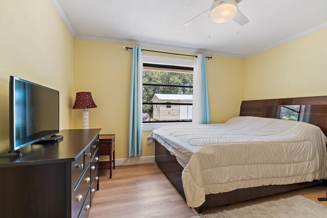 bedroom with crown molding, baseboards, ceiling fan, and light wood finished floors