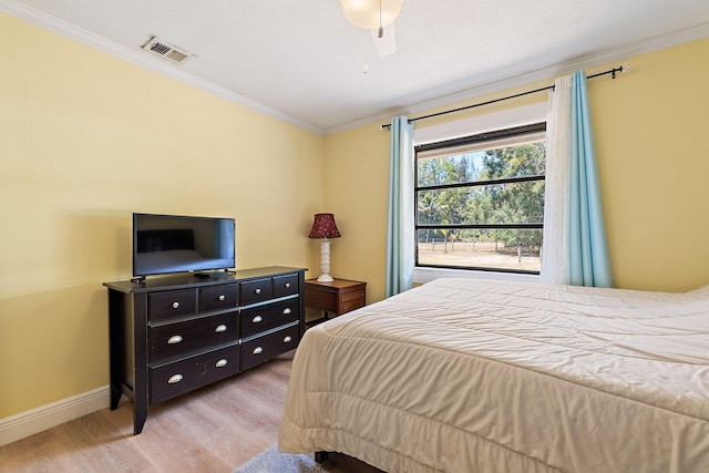 bedroom featuring crown molding, visible vents, baseboards, a ceiling fan, and light wood finished floors