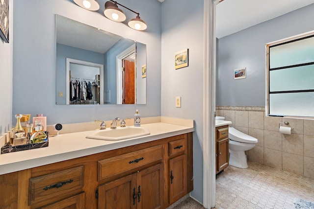full bathroom with wainscoting, vanity, toilet, tile patterned floors, and tile walls