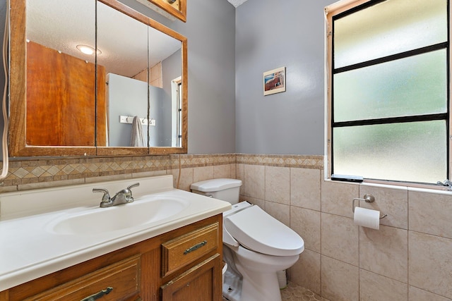 bathroom featuring toilet, tile walls, a wainscoted wall, and vanity
