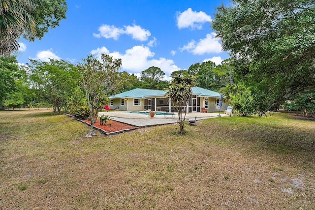 rear view of property with a lawn, a patio area, metal roof, and an outdoor pool