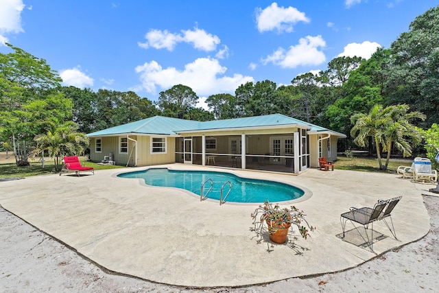 outdoor pool with a sunroom and a patio area