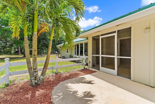 view of patio with fence and a sunroom