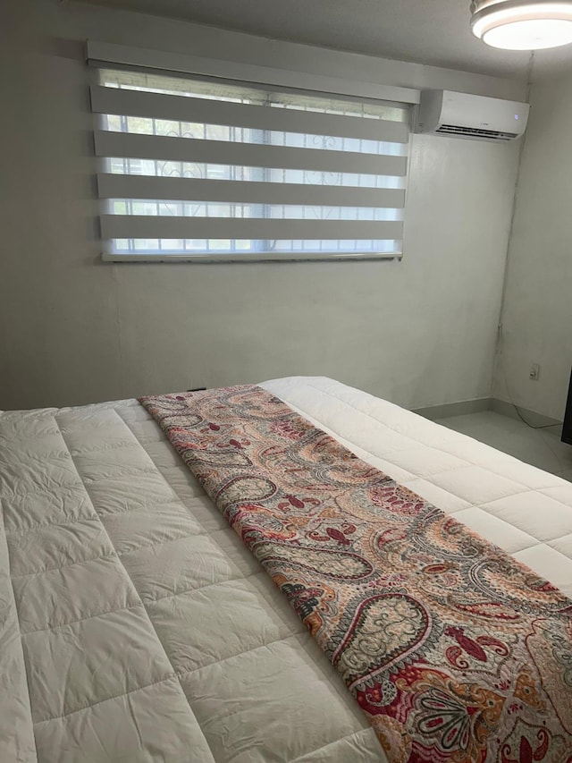 bedroom featuring light tile patterned floors and a wall unit AC
