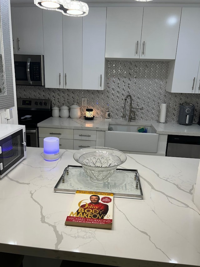 kitchen featuring a sink, appliances with stainless steel finishes, tasteful backsplash, and light stone countertops